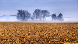 A Picturesque View Of A Farmhouse In The Rolling Hills Of Kansas Wallpaper