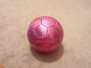 A Pink Soccer Ball On A Green Grass Field Wallpaper