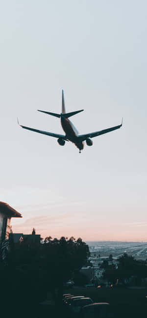 A Plane Flying Over A City Wallpaper