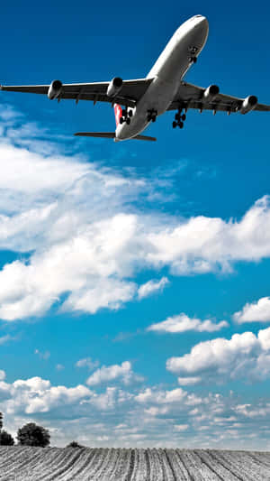 A Plane Flying Over A Field Wallpaper