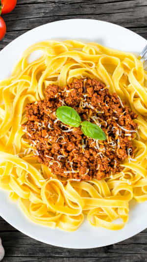 A Plate Of Pasta With Meat Sauce And Tomatoes Wallpaper