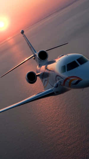 A Private Jet Flying Over The Ocean At Sunset Wallpaper