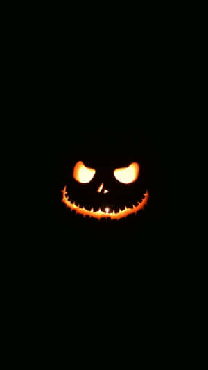 A Pumpkin With A Scary Face In The Dark Wallpaper