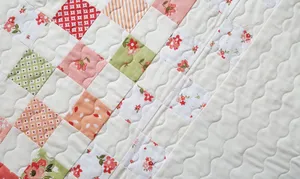 A Quilt With A Patchwork Pattern And Flowers Wallpaper