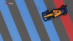 A Racing Car Driving Down A Track With Blue And Red Stripes Wallpaper