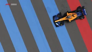 A Racing Car Driving Down A Track With Blue And Red Stripes Wallpaper