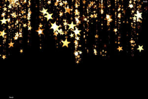 A Rain Of Golden Stars Cascades Through The Night Sky, Shining Bright In The Darkness. Wallpaper