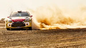A Rally Car Driving Through A Dusty Area Wallpaper
