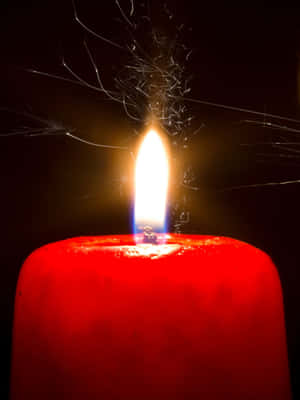 A Red Candle With A Spark Of Fire Wallpaper