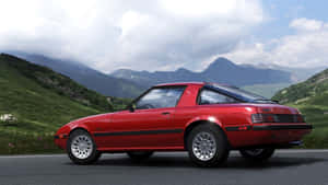 A Red Sports Car Driving Down A Mountain Road Wallpaper