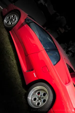 A Red Sports Car Is Parked In The Grass Wallpaper