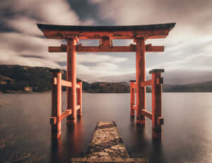 A Red Tori Gate Is Standing In The Water Wallpaper