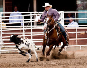 A Rider Clutching Their Cowboy Hat As They Balance On A Bucking Bronco At A Rodeo Wallpaper