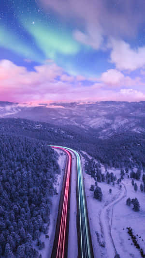 A Road With Lights And Aurora Borealis In The Sky Wallpaper