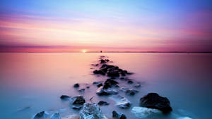 A Rock Line With A Sunset In The Background Wallpaper