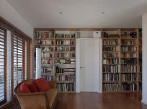 A Room With A Couch And Bookshelves Wallpaper