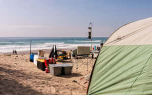 A Serene Beach Campsite During Sunset Wallpaper