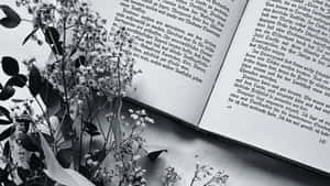 A Single Open Book In Black And White On A Wooden Table Wallpaper