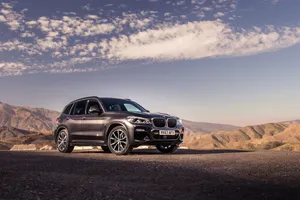 A Sleek Black Bmw X3 With A Dramatic Background Wallpaper