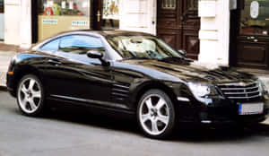 A Sleek Black Chrysler Crossfire On A Picturesque Highway Wallpaper