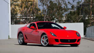 A Sleek, Red Ferrari 599 Gtb Fiorano Speedily Traversing An Urban Landscape Wallpaper