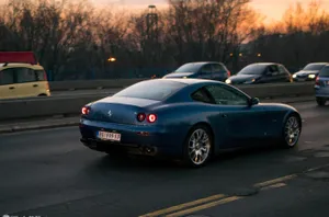 A Sleek Red Ferrari 612 Scaglietti Against A Scenic Countryside Backdrop. Wallpaper