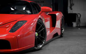 A Sleek Red Ferrari Enzo Parked Outdoors Wallpaper