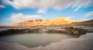 A Small Pool In The Desert With Mountains In The Background Wallpaper