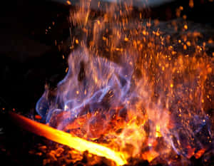 A Smart Blacksmith Stands Over A Blazing Forge And Hard At Work. Wallpaper