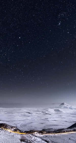 A Snowy Landscape With A Road And Stars Above It Wallpaper