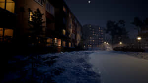 A Snowy Street With Buildings And Lights At Night Wallpaper