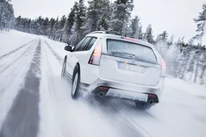 A Snowy Winter Road With A Car Driving Through The Picturesque Landscape Wallpaper