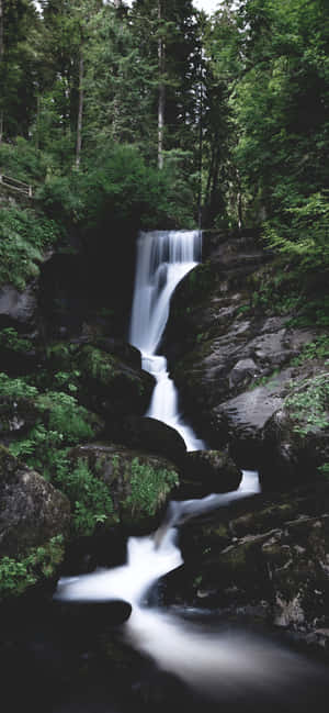 A Spectacular Waterfall Cascading Down A Mountainside Wallpaper