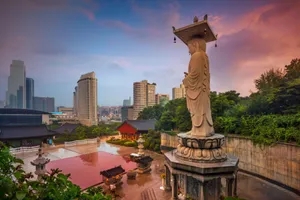 A Statue Of A Buddha In Front Of A City Wallpaper