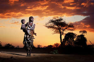 A Statue Of A Woman And Child Standing In The Desert Wallpaper