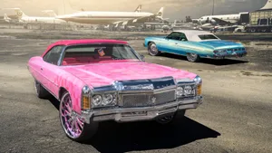 A Striking Pink Vintage Car Resting In The Countryside. Wallpaper