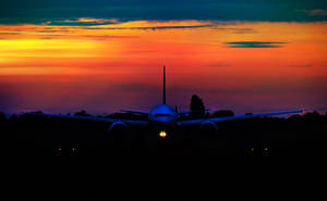 A Stunning Aerial View Of The Sun Setting Below An Airplane Wallpaper