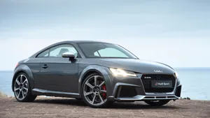 A Stunning Audi Tt Drives Down A Scenic Road Wallpaper