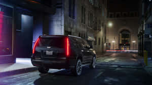 A Stunning Black Cadillac Escalade On The Road Wallpaper