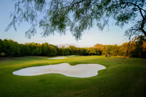 A Stunning Golf Green In Pristine Condition Under A Blue Sky Wallpaper