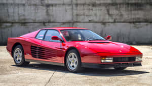 A Stunning Red 1984 Ferrari Testarossa Posed Against A Striking Cityscape Backdrop Wallpaper