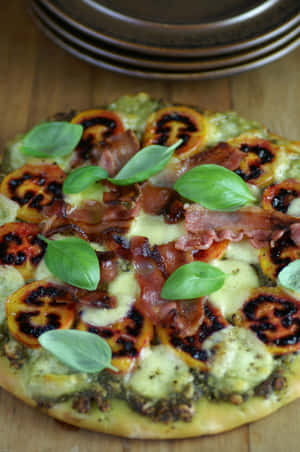 A Sumptuous Tamarillo Pizza Garnished With Fresh Basil Leaves Wallpaper