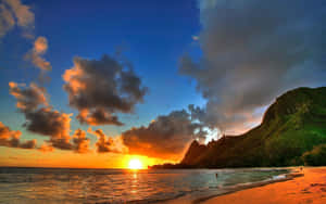 A Sunset Over A Beach With Mountains In The Background Wallpaper