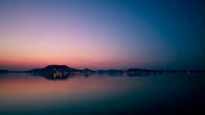 A Sunset Over A Lake With Mountains In The Background Wallpaper