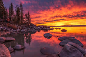 A Sunset Over A Lake With Rocks And Trees Wallpaper