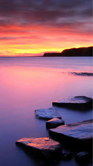 A Sunset With Rocks In The Water Wallpaper