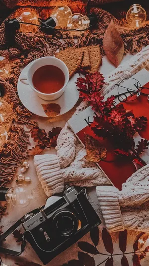 A Table With A Cup Of Tea, A Camera And Leaves Wallpaper