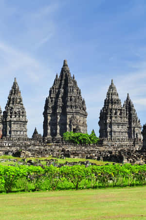 A Temple With Many Stone Statues In The Grass Wallpaper