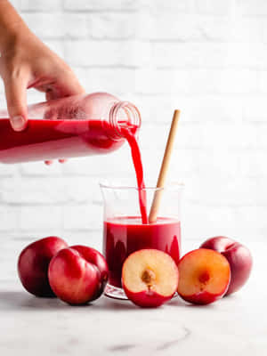 A Vibrant Image Of Fresh And Juicy Red Plums On A Wooden Table Wallpaper