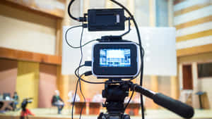 A Video Camera Is On A Tripod In A Large Auditorium Wallpaper